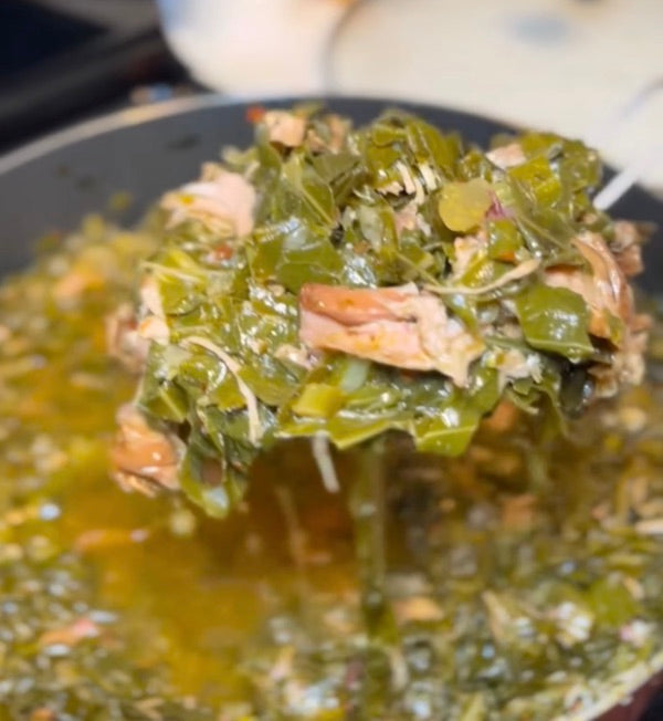 A ladle lifting braised collard greens and shredded turkey from a pot of broth