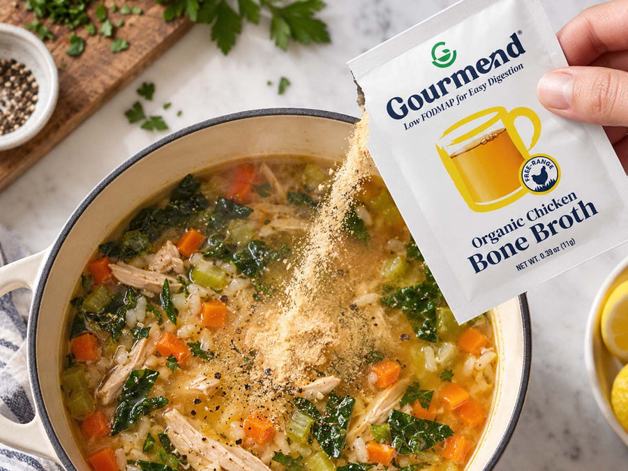 A hand sprinkling Gourmend chicken bone broth powder into a pot of chicken, rice and vegetable soup