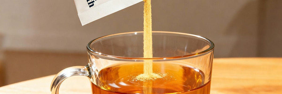 Broth powder pouring from a Gourmend packet into a glass mug of hot broth